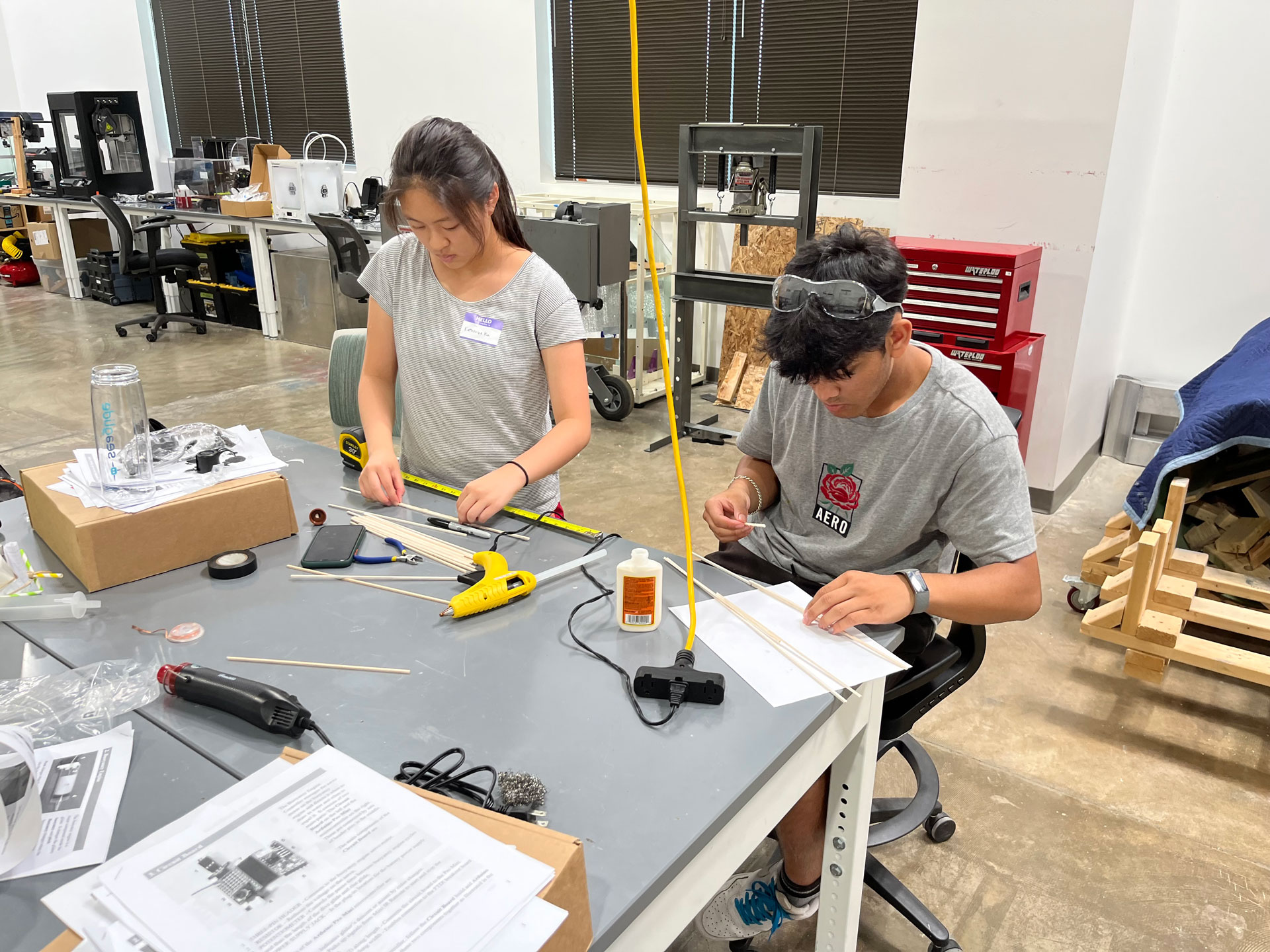 Two high school students use are binding cables together to build their remotely operated vehicle