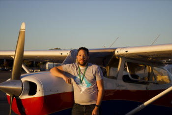 A man stands in front of a small plane